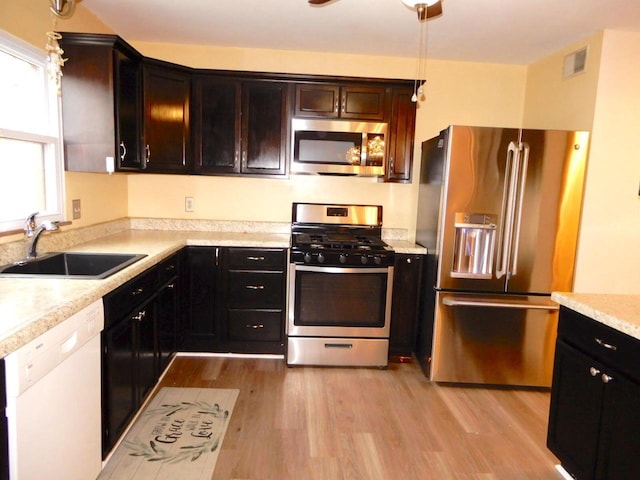 kitchen featuring a sink, stainless steel appliances, light wood-type flooring, visible vents, and light countertops