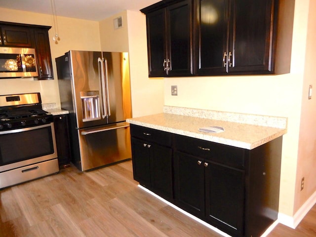 kitchen featuring appliances with stainless steel finishes, visible vents, and light wood finished floors