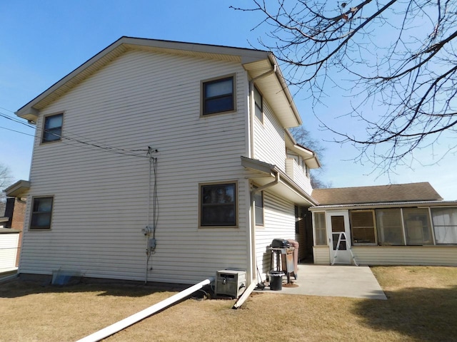 rear view of house featuring a sunroom, a patio area, and a lawn