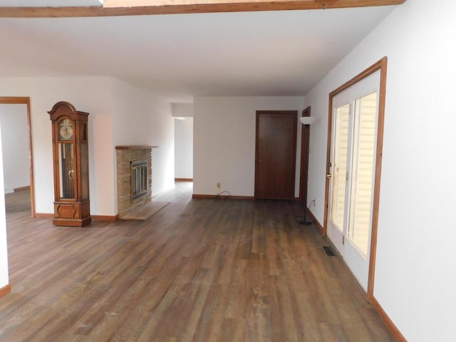 unfurnished living room featuring baseboards, a stone fireplace, wood finished floors, and visible vents