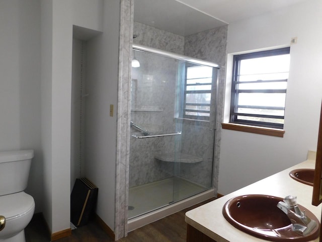 full bath featuring double vanity, a sink, a stall shower, and toilet
