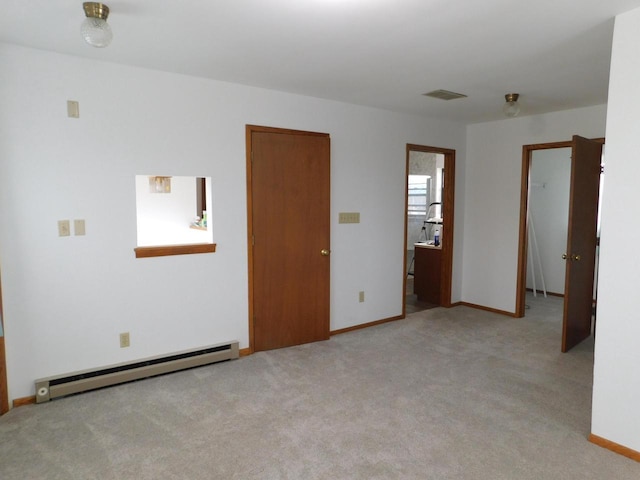 empty room with baseboards, baseboard heating, carpet flooring, and visible vents
