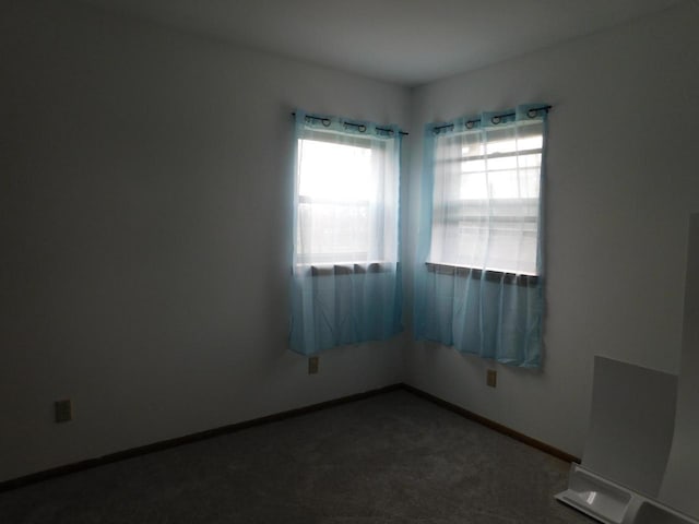 empty room with baseboards and dark carpet