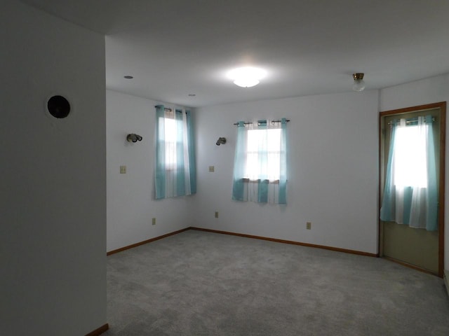 unfurnished room featuring baseboards, plenty of natural light, and carpet