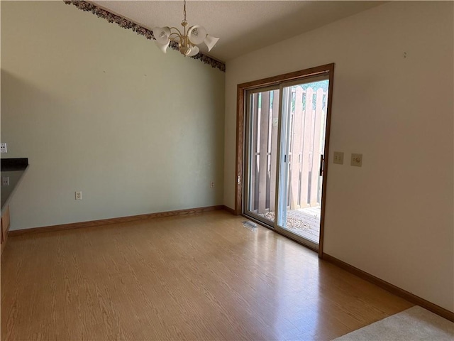 unfurnished room featuring baseboards, a chandelier, and light wood-style floors