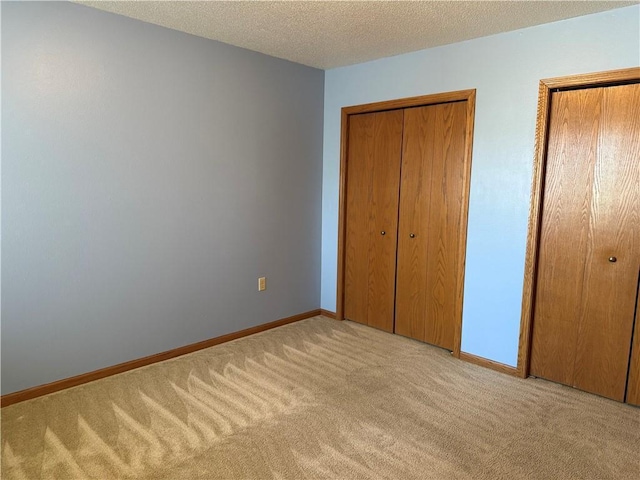 unfurnished bedroom with baseboards, a textured ceiling, and carpet