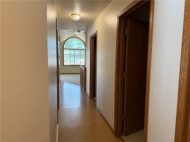 corridor featuring baseboards and a textured ceiling