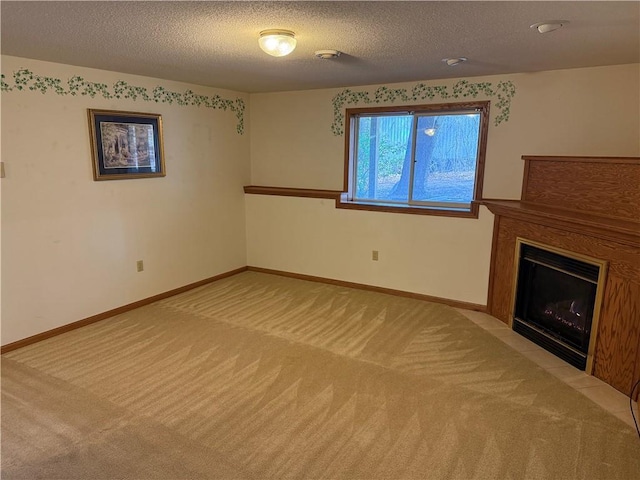 unfurnished living room with light colored carpet, a fireplace with flush hearth, a textured ceiling, and baseboards