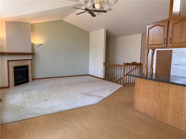 unfurnished living room with baseboards, a ceiling fan, light wood-style flooring, and vaulted ceiling