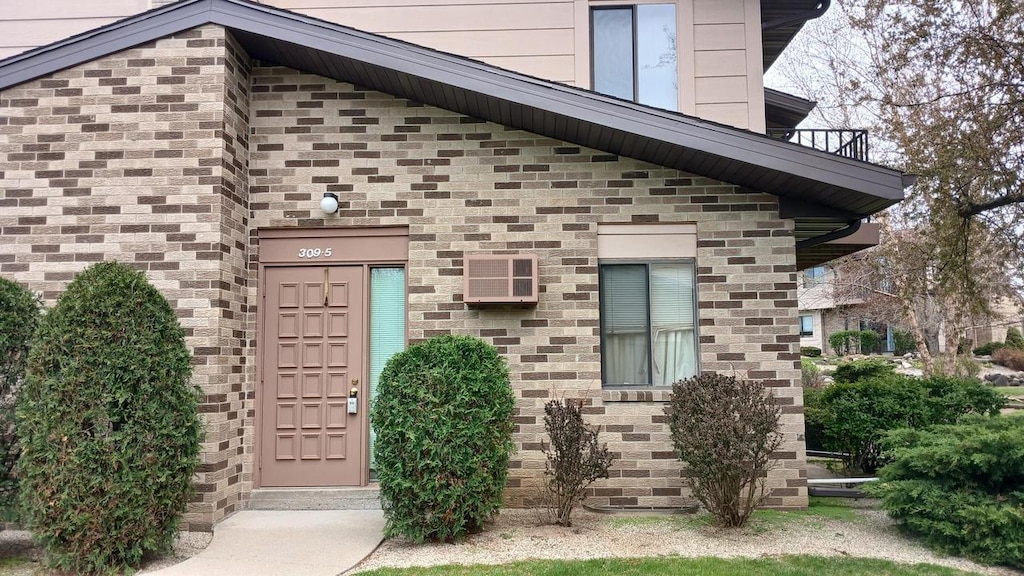 doorway to property featuring a wall mounted AC and a balcony