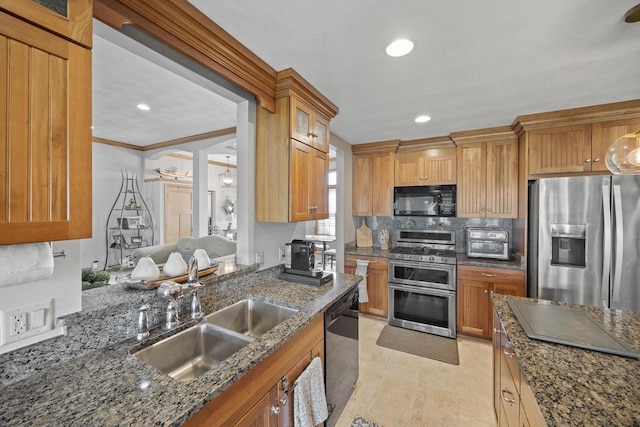 kitchen with dark stone counters, backsplash, appliances with stainless steel finishes, and a sink