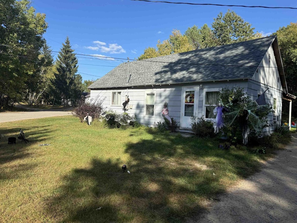 exterior space featuring roof with shingles and a front lawn