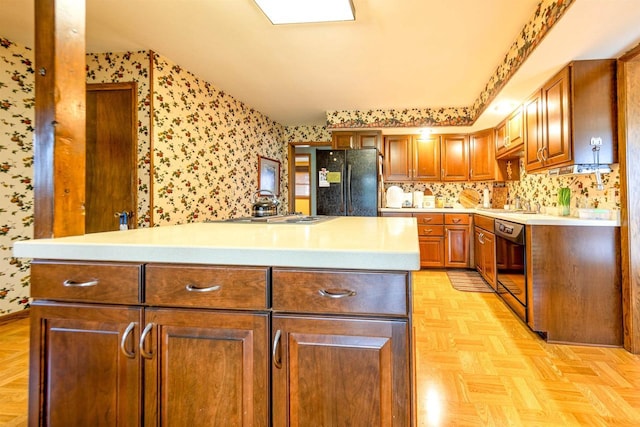 kitchen featuring black appliances, light countertops, wallpapered walls, and a center island