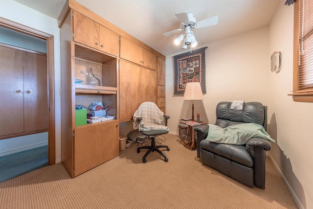 home office featuring a ceiling fan, light colored carpet, and baseboards