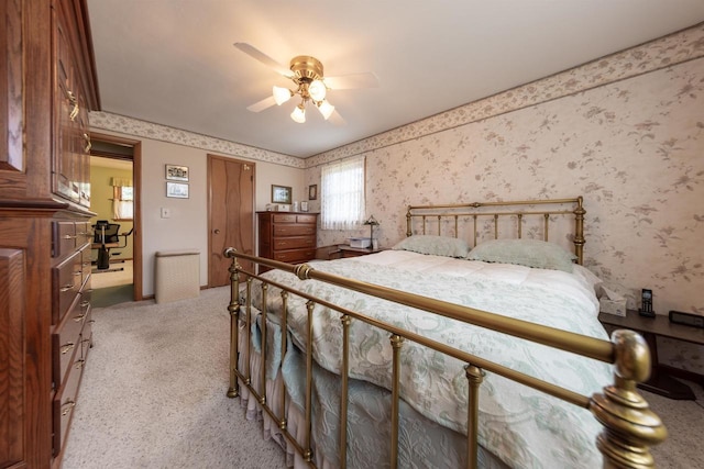bedroom with a ceiling fan, wallpapered walls, and light carpet