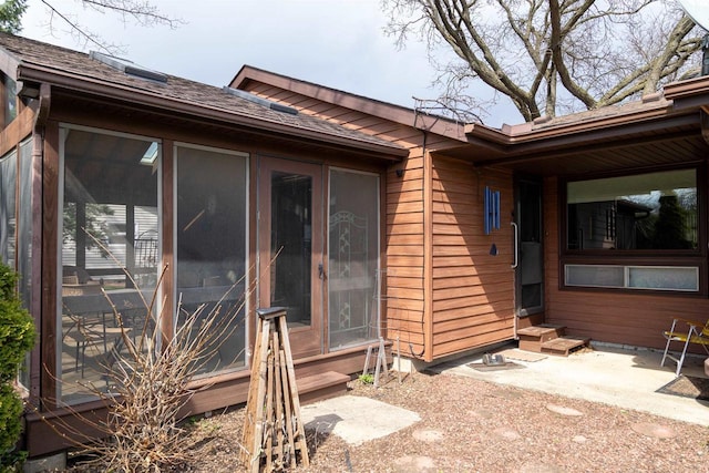 view of exterior entry with roof with shingles