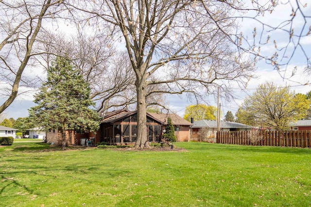 view of yard with fence and a sunroom