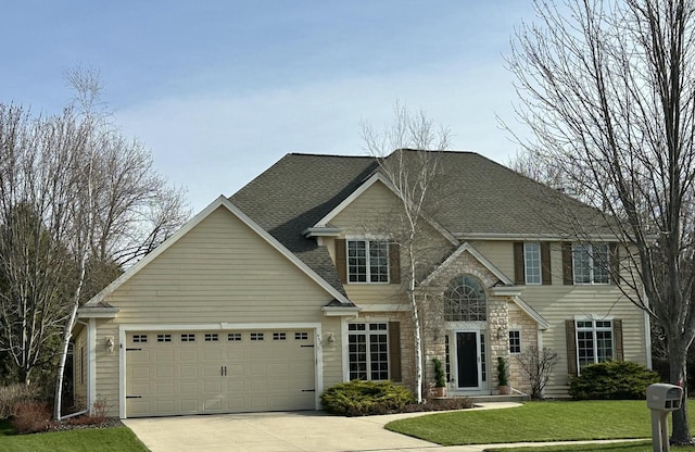 view of front facade featuring a front yard, stone siding, a shingled roof, concrete driveway, and an attached garage
