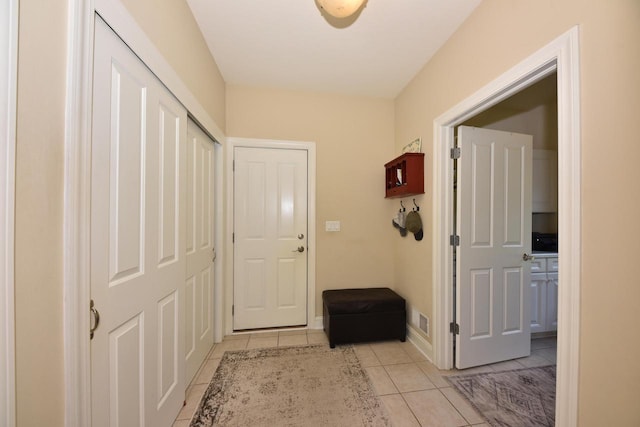 doorway to outside featuring baseboards, visible vents, and light tile patterned floors