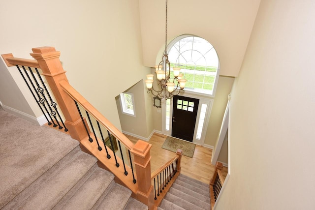 entryway with stairway, baseboards, a chandelier, and a towering ceiling