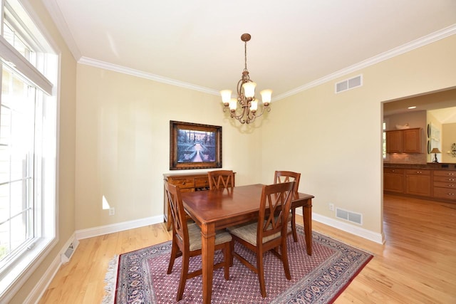 dining space featuring visible vents, ornamental molding, and light wood-style flooring