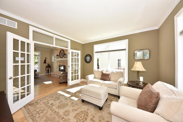living area with crown molding, french doors, wood finished floors, and visible vents