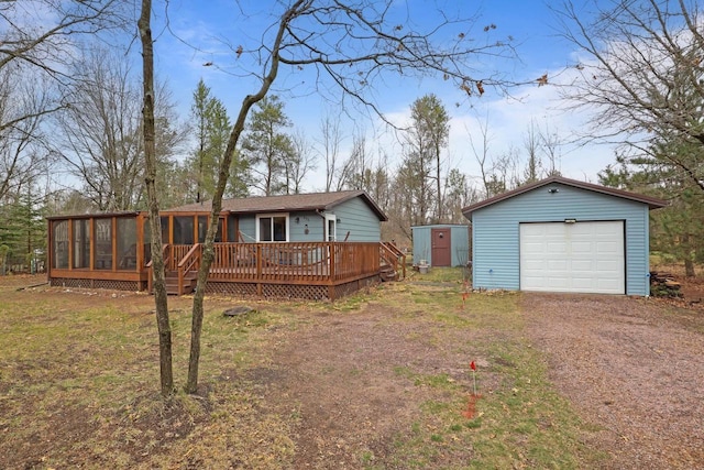 996 Inverness Ct, Nekoosa, WI 54457 - view of front of home with a sunroom, an outdoor structure, a garage, dirt driveway, and a wooden deck