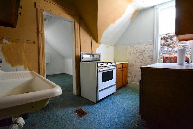 kitchen featuring brown cabinetry, light countertops, carpet, white gas stove, and lofted ceiling