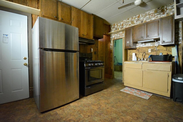kitchen featuring a sink, gas range oven, light countertops, freestanding refrigerator, and a ceiling fan