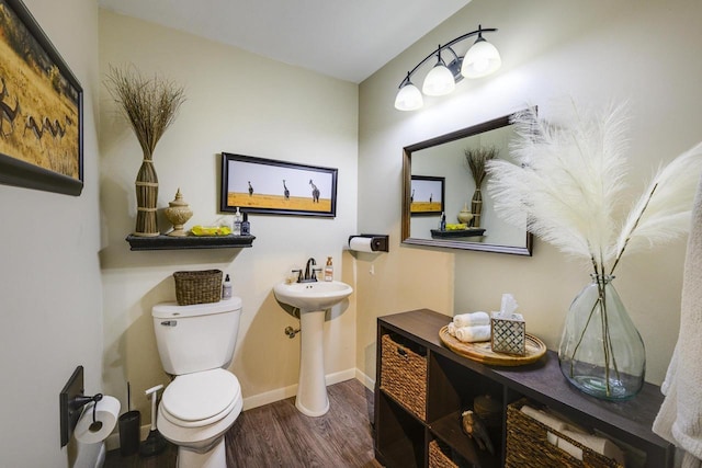 229 N Ludington St, Columbus, WI 53925 - half bath featuring toilet, baseboards, a sink, and wood finished floors