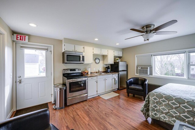229 N Ludington St, Columbus, WI 53925 - kitchen with radiator, wood finished floors, white cabinetry, and stainless steel appliances