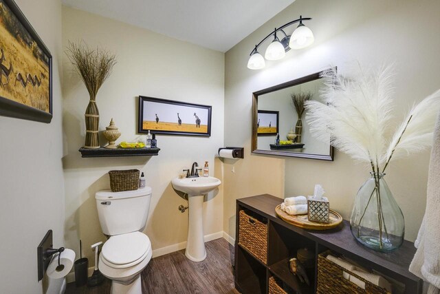 229 N Ludington St, Columbus, WI 53925 - half bath featuring toilet, baseboards, a sink, and wood finished floors