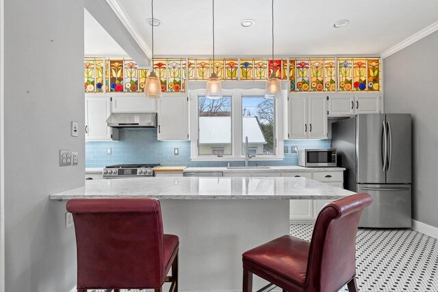 745 S Quincy St, Green Bay, WI 54301 - kitchen with decorative backsplash, appliances with stainless steel finishes, white cabinets, wall chimney exhaust hood, and a kitchen breakfast bar