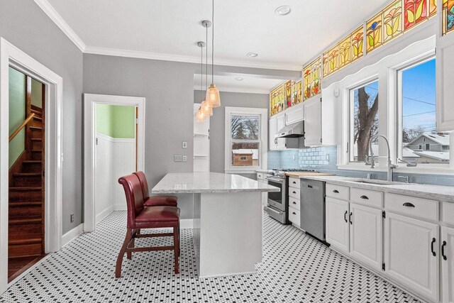 745 S Quincy St, Green Bay, WI 54301 - kitchen with crown molding, white cabinets, a sink, appliances with stainless steel finishes, and under cabinet range hood