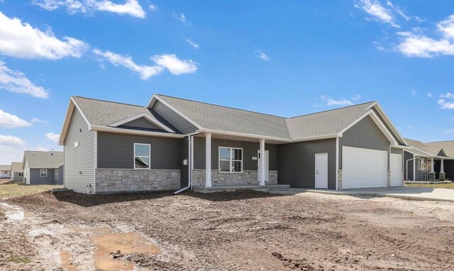 2081 Antelope Trl, Kaukauna, WI 54130 - view of front of home with concrete driveway, stone siding, roof with shingles, an attached garage, and a porch