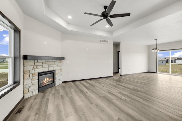 2081 Antelope Trl, Kaukauna, WI 54130 - unfurnished living room featuring a raised ceiling, visible vents, light wood finished floors, and a stone fireplace