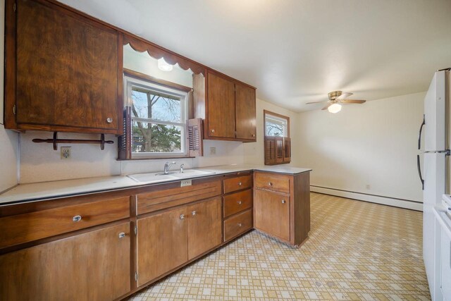 167 Gwynn St, Green Bay, WI 54301 - kitchen with a sink, light countertops, a baseboard heating unit, light floors, and a ceiling fan