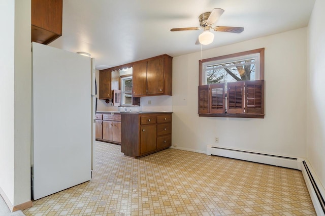 167 Gwynn St, Green Bay, WI 54301 - kitchen with ceiling fan, brown cabinetry, baseboards, freestanding refrigerator, and a baseboard radiator