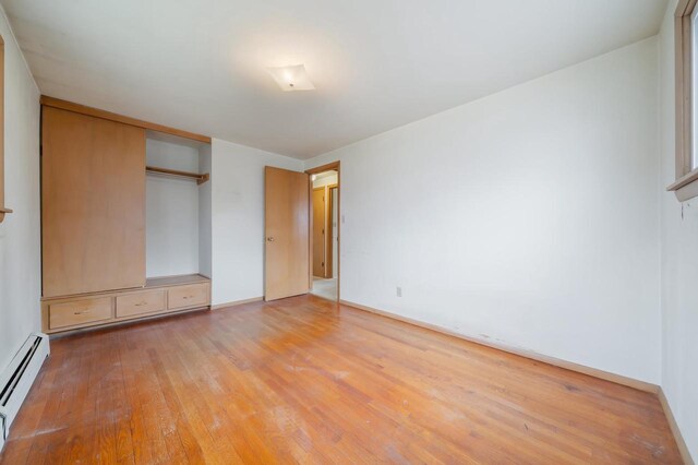 167 Gwynn St, Green Bay, WI 54301 - unfurnished bedroom with a closet, baseboard heating, hardwood / wood-style flooring, and baseboards