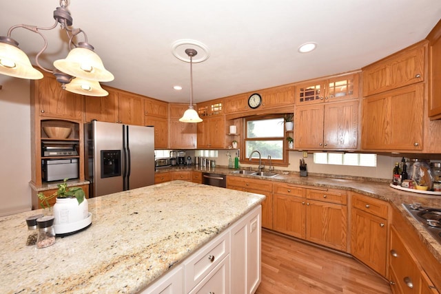 kitchen with light stone counters, open shelves, light wood-style floors, appliances with stainless steel finishes, and a sink