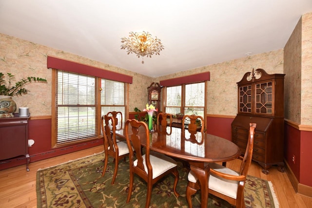 dining space featuring wainscoting, light wood-type flooring, and wallpapered walls