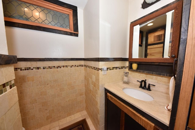 bathroom featuring vanity, a wainscoted wall, and tile walls