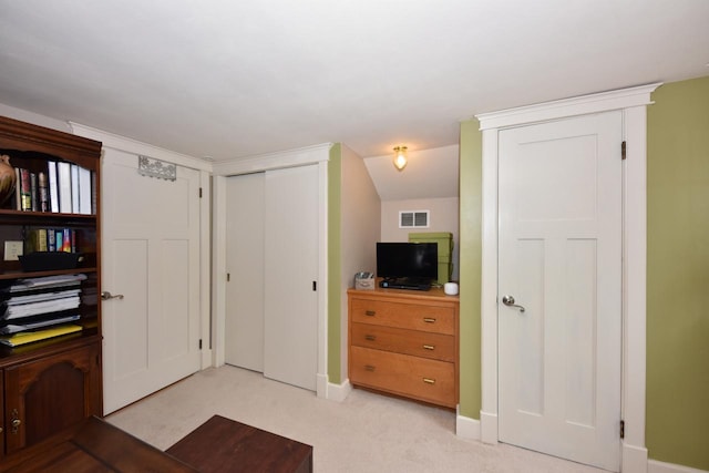 interior space featuring light colored carpet, visible vents, multiple closets, and baseboards