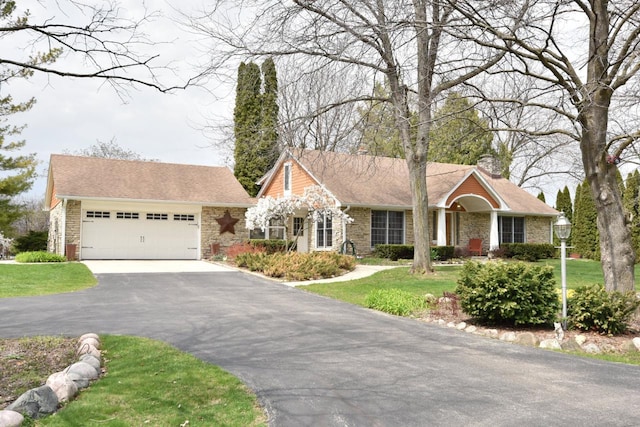 single story home featuring a front lawn, a garage, driveway, stone siding, and a chimney