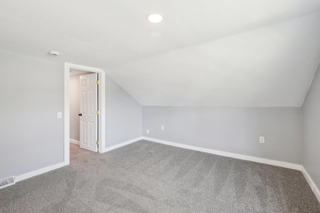 additional living space with visible vents, carpet, baseboards, and vaulted ceiling