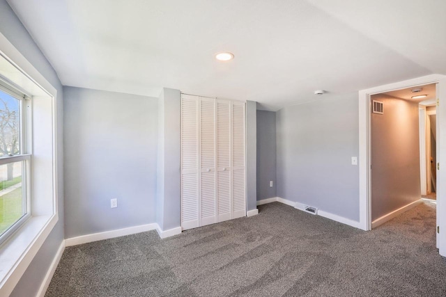 unfurnished bedroom with visible vents, carpet floors, multiple windows, and a closet