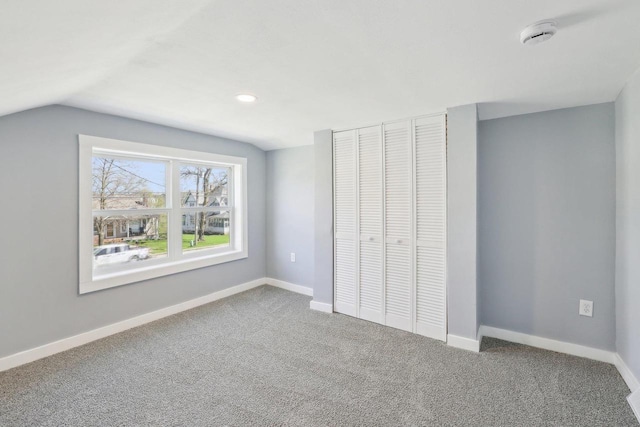 unfurnished bedroom with baseboards, lofted ceiling, carpet, and a closet