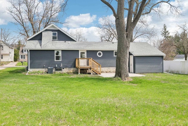 back of property with a yard, fence, and a shingled roof