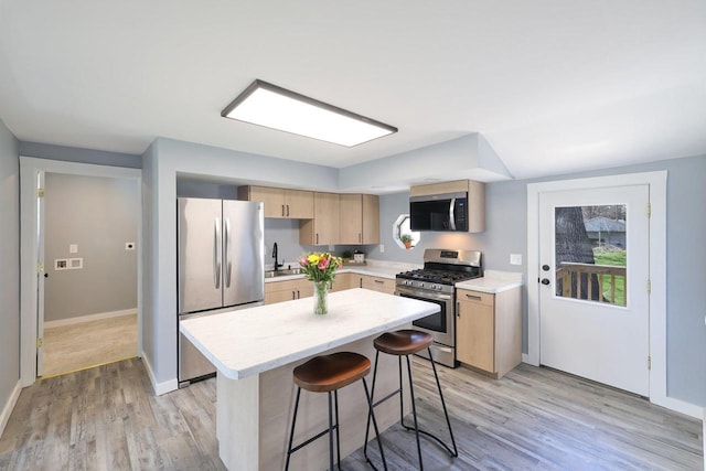 kitchen featuring light countertops, light brown cabinetry, stainless steel appliances, and light wood-style flooring
