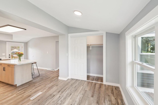 kitchen featuring visible vents, light countertops, light wood finished floors, and lofted ceiling